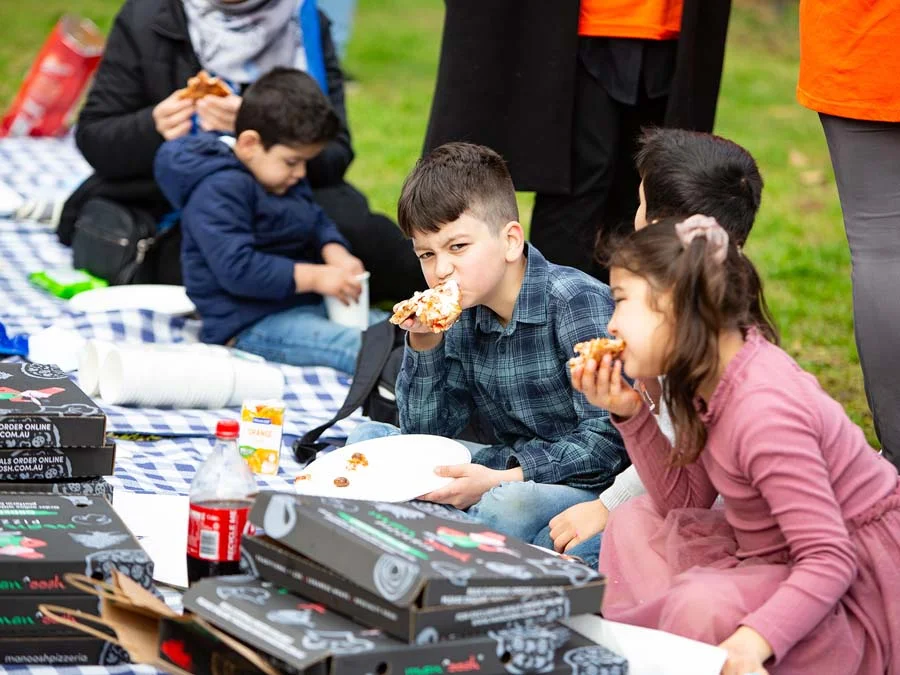 Small children enjoying pizza together at SSI Welcome Program event