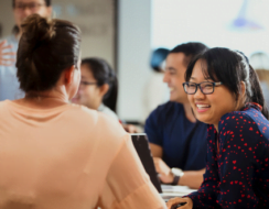 A group of people sitting at a desk in an office talking