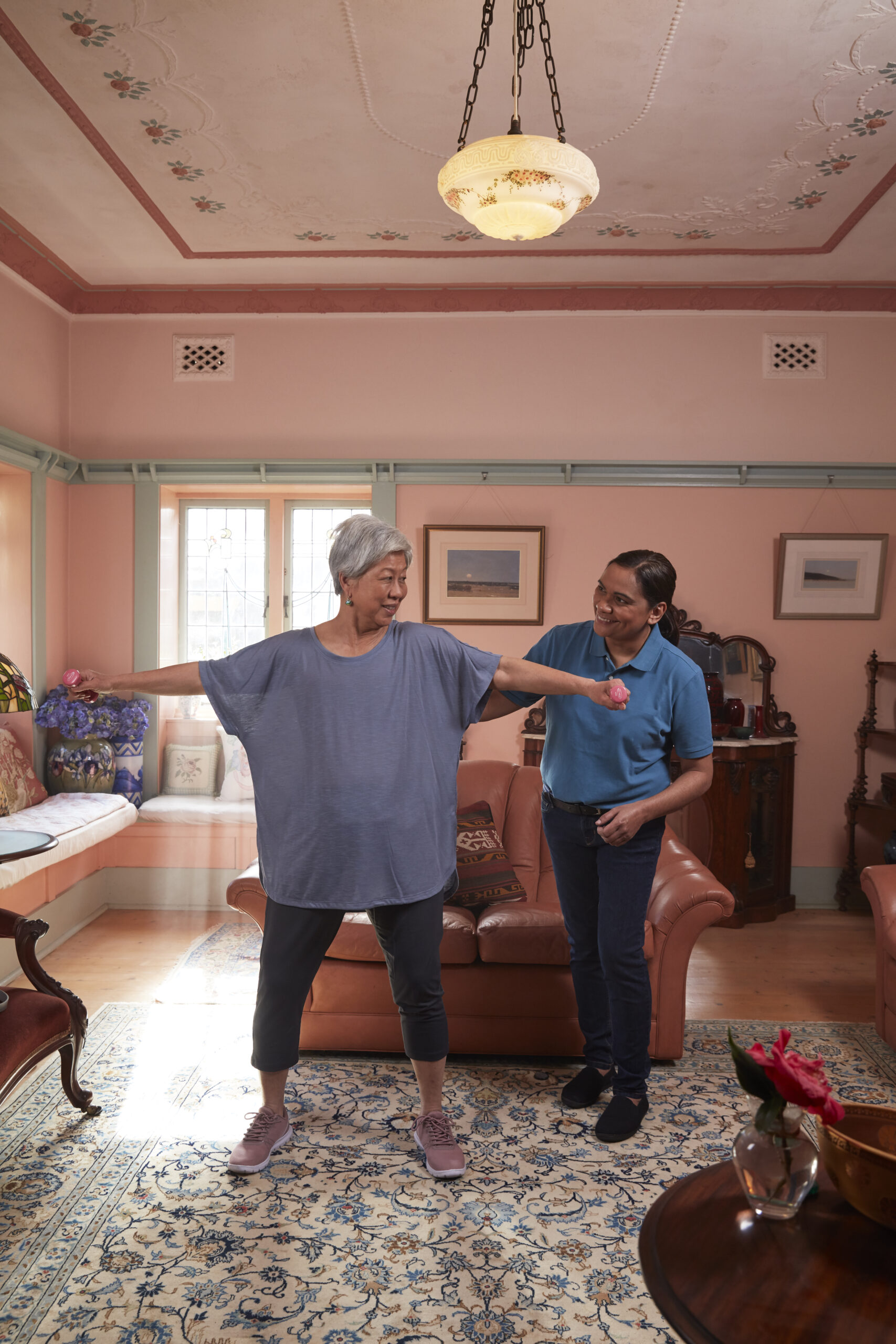 Home care worker helping senior woman exercise