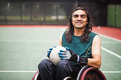 Man in a wheelchair playing sport outdoors on a court