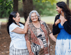 Three women from Indigenous backgrounds smile.