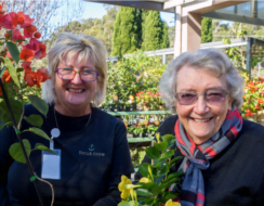 Two ladies smile amidst many flowers