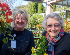 Two ladies smile amidst many flowers