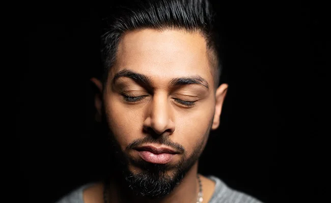 Man with eyes closed up close with dark background