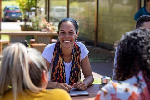 Woman smiling in conversation with others.