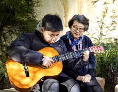 Child playing guitar with grandmother
