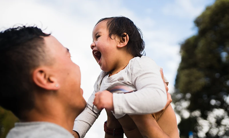 Dad holding a young smiling child in the air