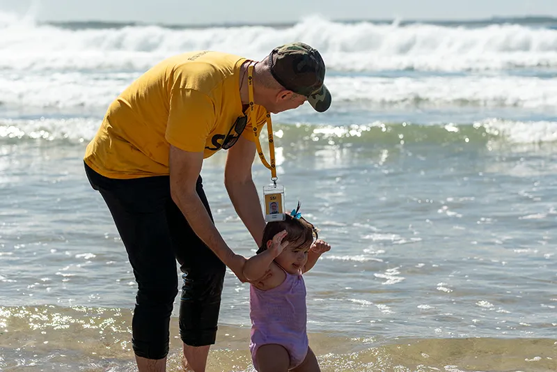 Joseph Sando with a young child at the beach, SSI Welcomed to Welcomer